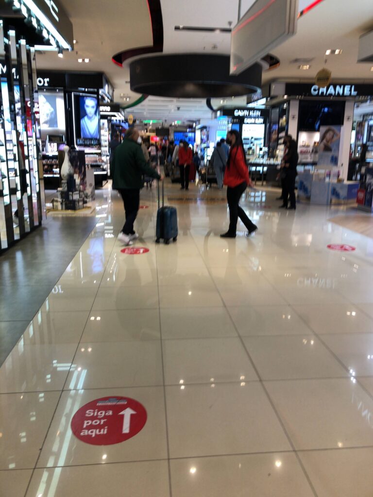 グアルーリョス空港の免税店エリアを歩く旅行者とブランドショップの様子