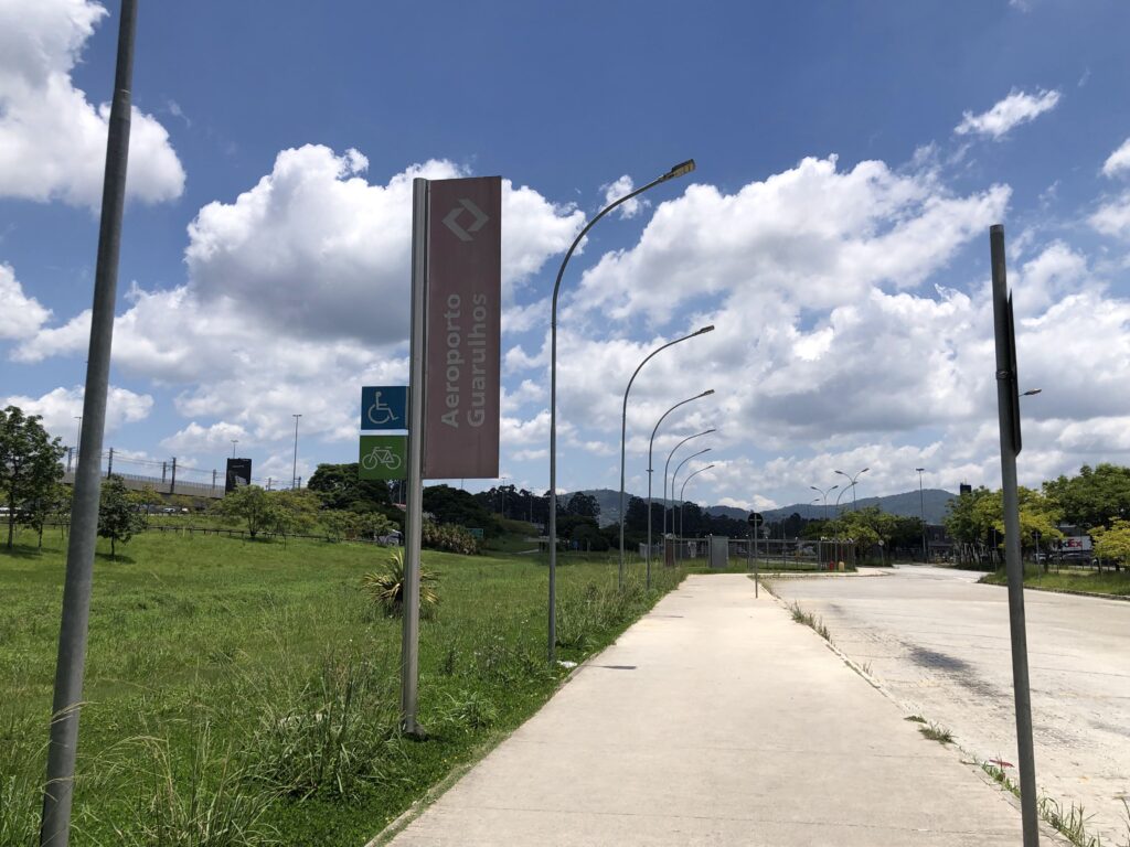 グアルーリョス空港駅の外に立つ「Aeroporto Guarulhos」標識と周辺の風景