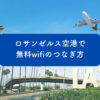 ロサンゼルス空港（LAX）のターミナルで、iPhoneが「_LAX Free WiFi」接続画面を表示している様子。旅行者が無料WiFiにつなぐイメージ写真。