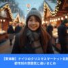 ドイツのクリスマスマーケットで笑顔の女性、木製屋台とイルミネーションに囲まれた冬の風景