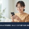 スマートフォンを見ながら笑顔で貯金残高を確認する主婦。自宅のリビングで、Wealthfrontを使ったシンプルなお金管理のイメージ。